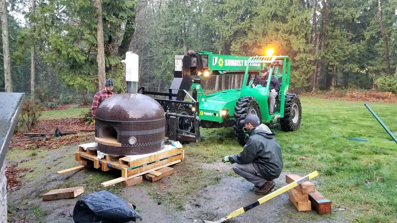 A crane lifting and installing a pizza oven