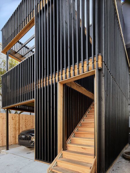 The wood slats were Fell’s idea, which Eric immediately jumped on. Depending on the angle, they provide a degree of privacy and shade, not to mention giving the home its attention-grabbing facade. Eric and his girlfriend relax on the balcony’s all-weather furniture by Ebel. Cedar trim and stairs add some contrasting color.