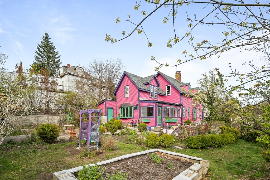 The exterior and backyard of a pink Victorian house