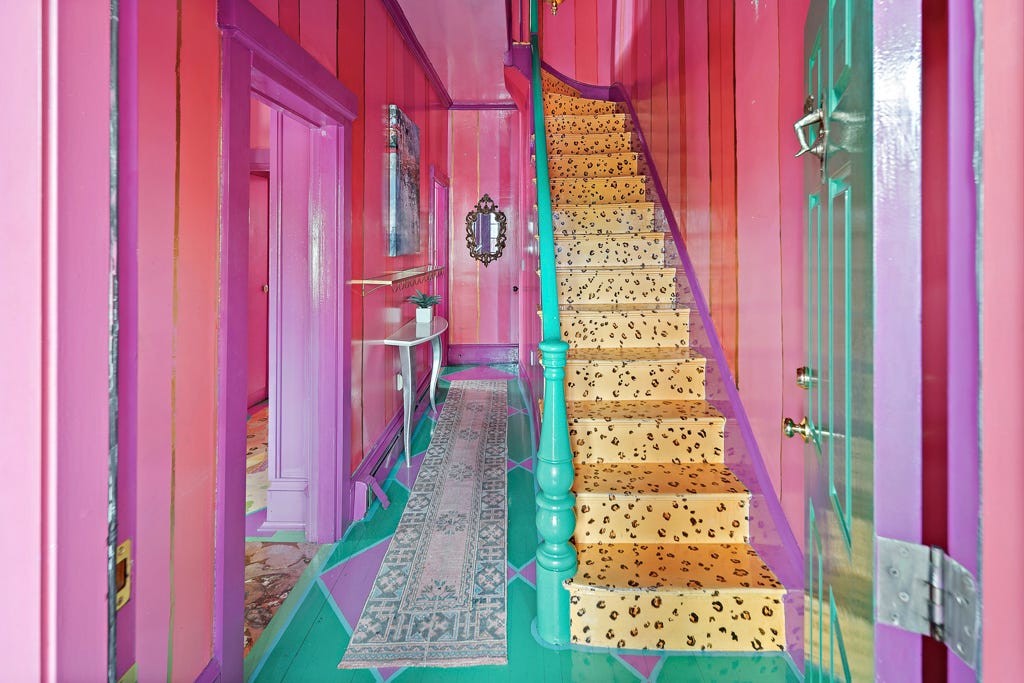 A pink hallway and a staircase with a cheetah print floor design