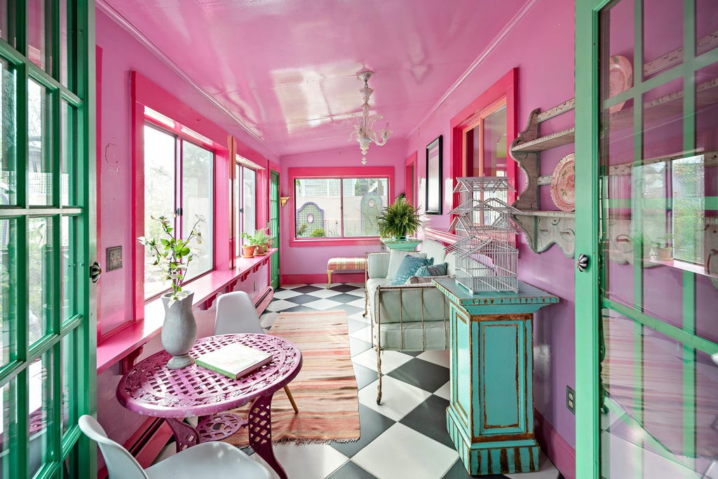 A sunroom with black and wile tile floor and pink walls