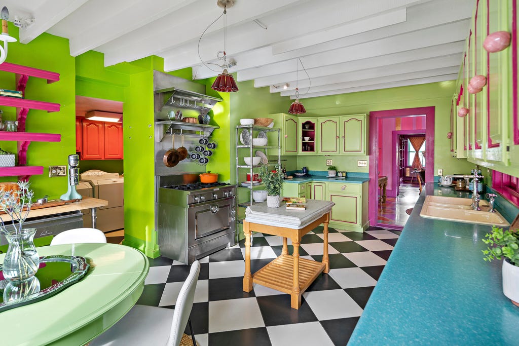 A lime green kitchen with black and white tiles and green cabinets