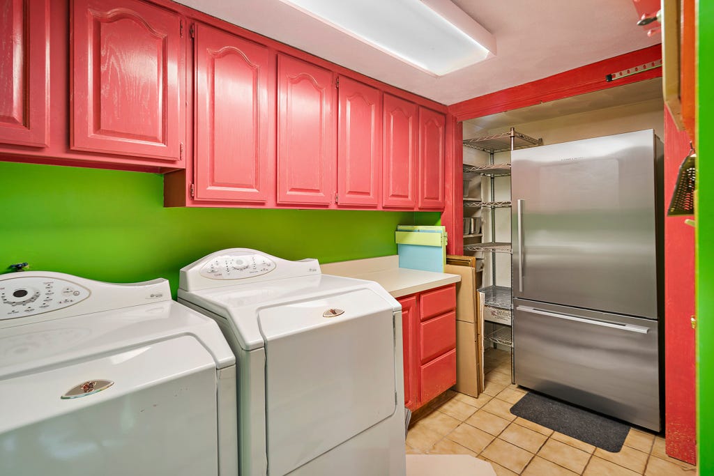 A laundry room with a refrigerator and green walls