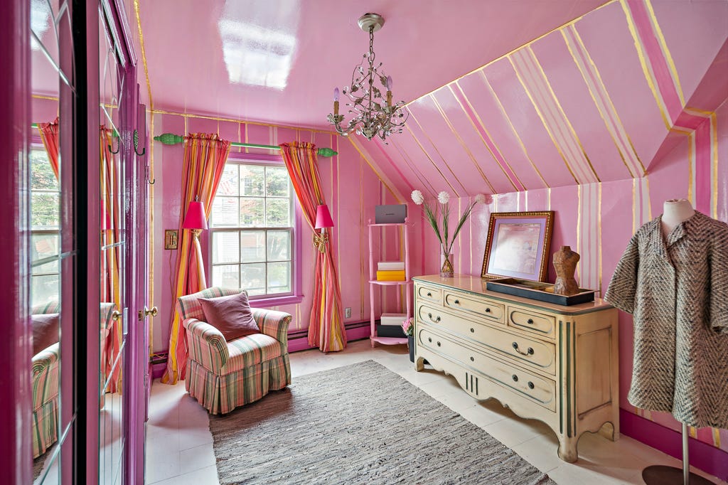 A dressing room with pink and gold walls and a glossy pink ceiling