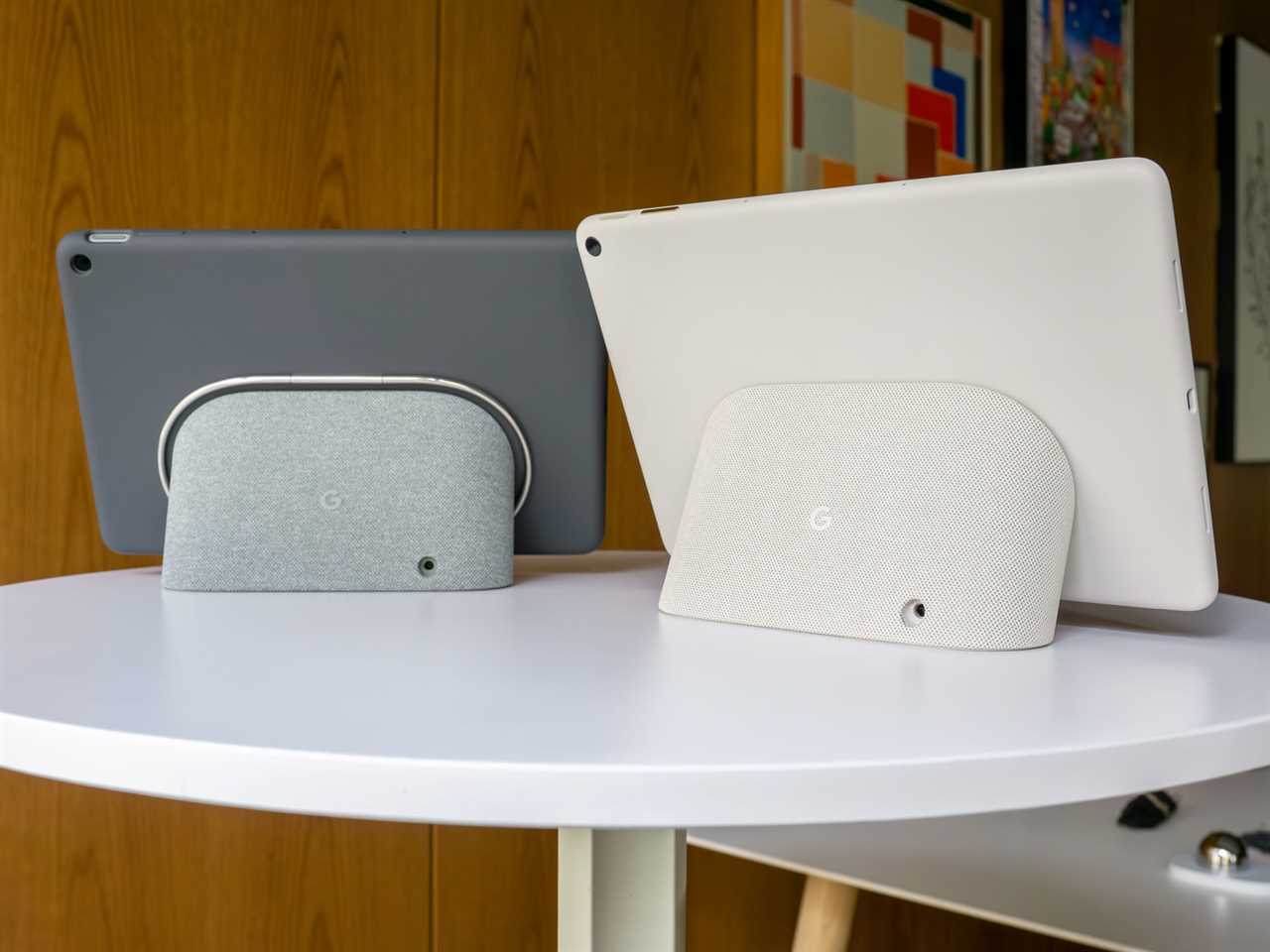 Two Google Pixel Tablets side by side showing their backs connected to their charging speaker docks.