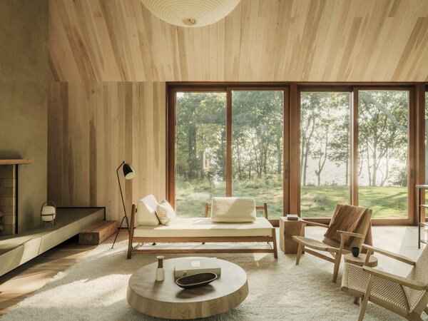 Inside, wood floors, walls, and ceilings along with wood-framed windows and doors nod to the region's history of timber construction. In the main living area, a daybed by Peca is complemented by side chairs from Carl Hansen and a coffee table from Black Creek Mercantile.