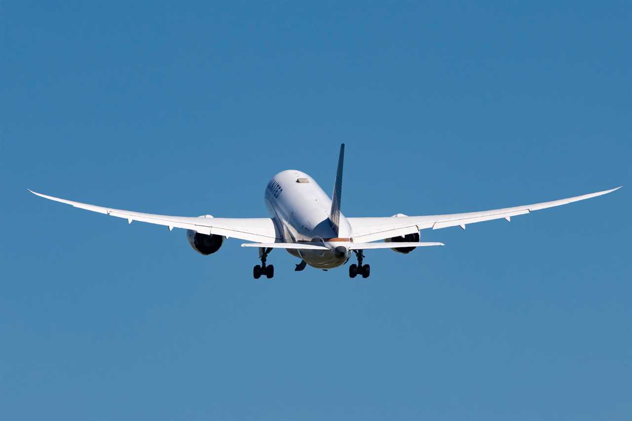 A United Airlines 787-8 Dreamliner photographed from the back while taking off from Amsterdam Schiphol airport in a blue sky day.