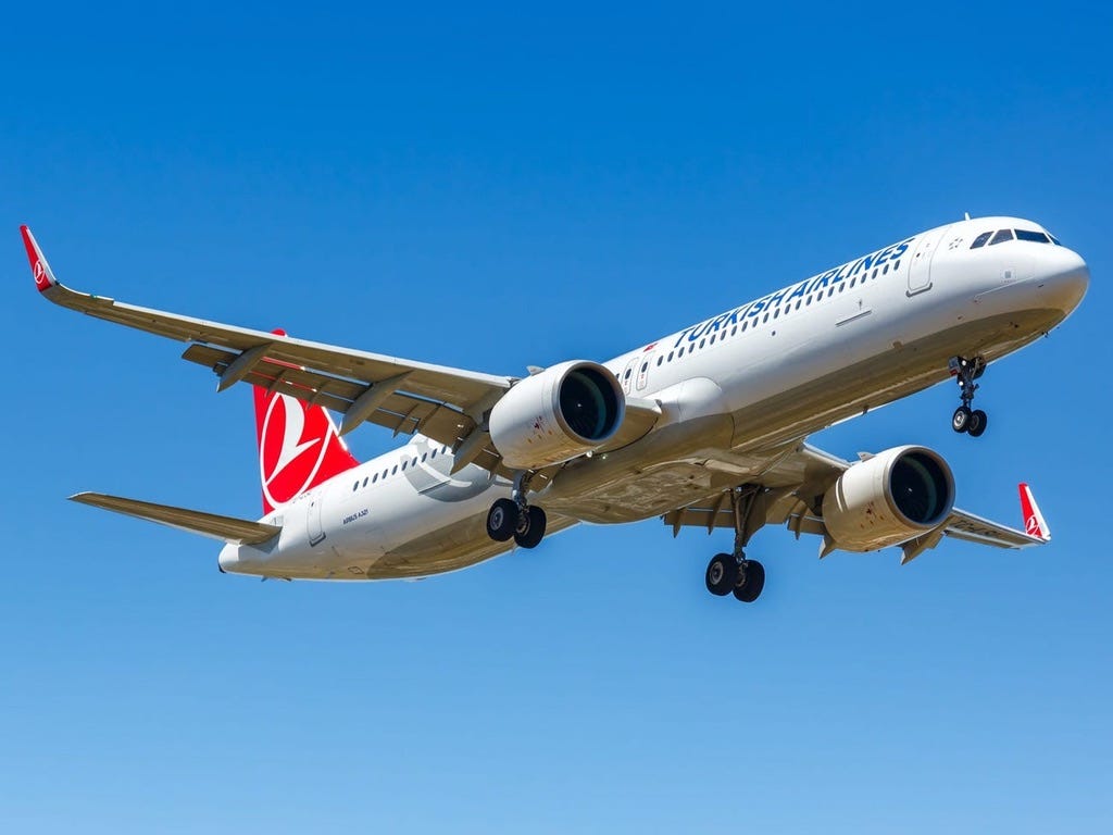 Turkish Airlines aircraft, white and red, over a blue sky.