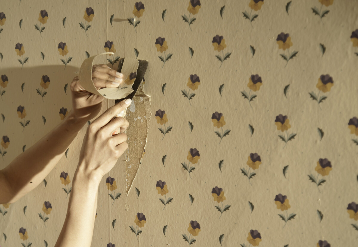 Close up of a hand scraping away wallpaper _ getty