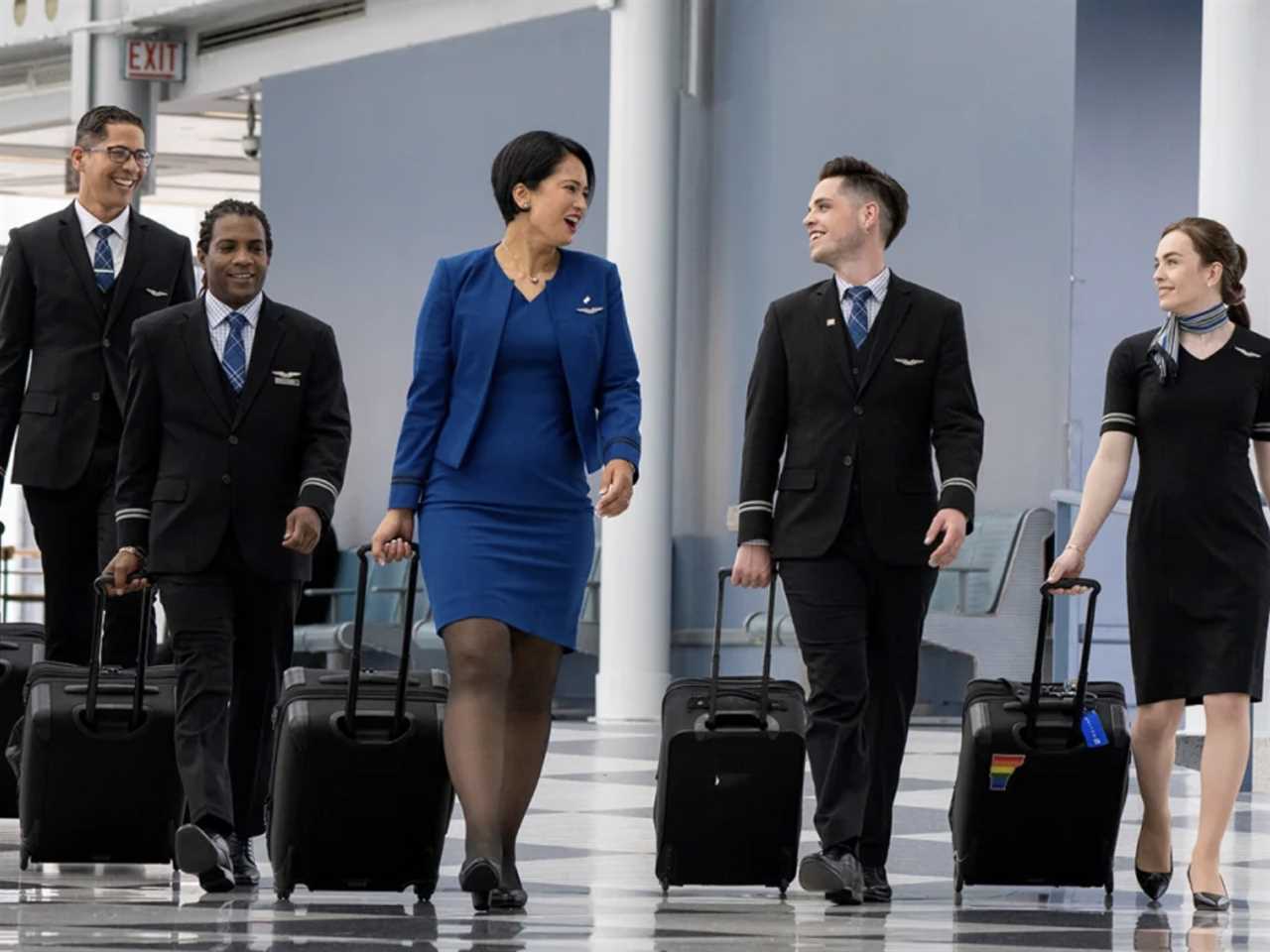 United Airlines flight attendants walking through an airport with roller bags.