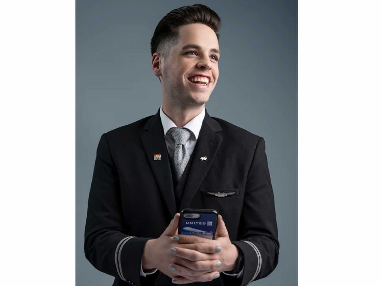 Male flight attendant holding a phone with teal nail polish.