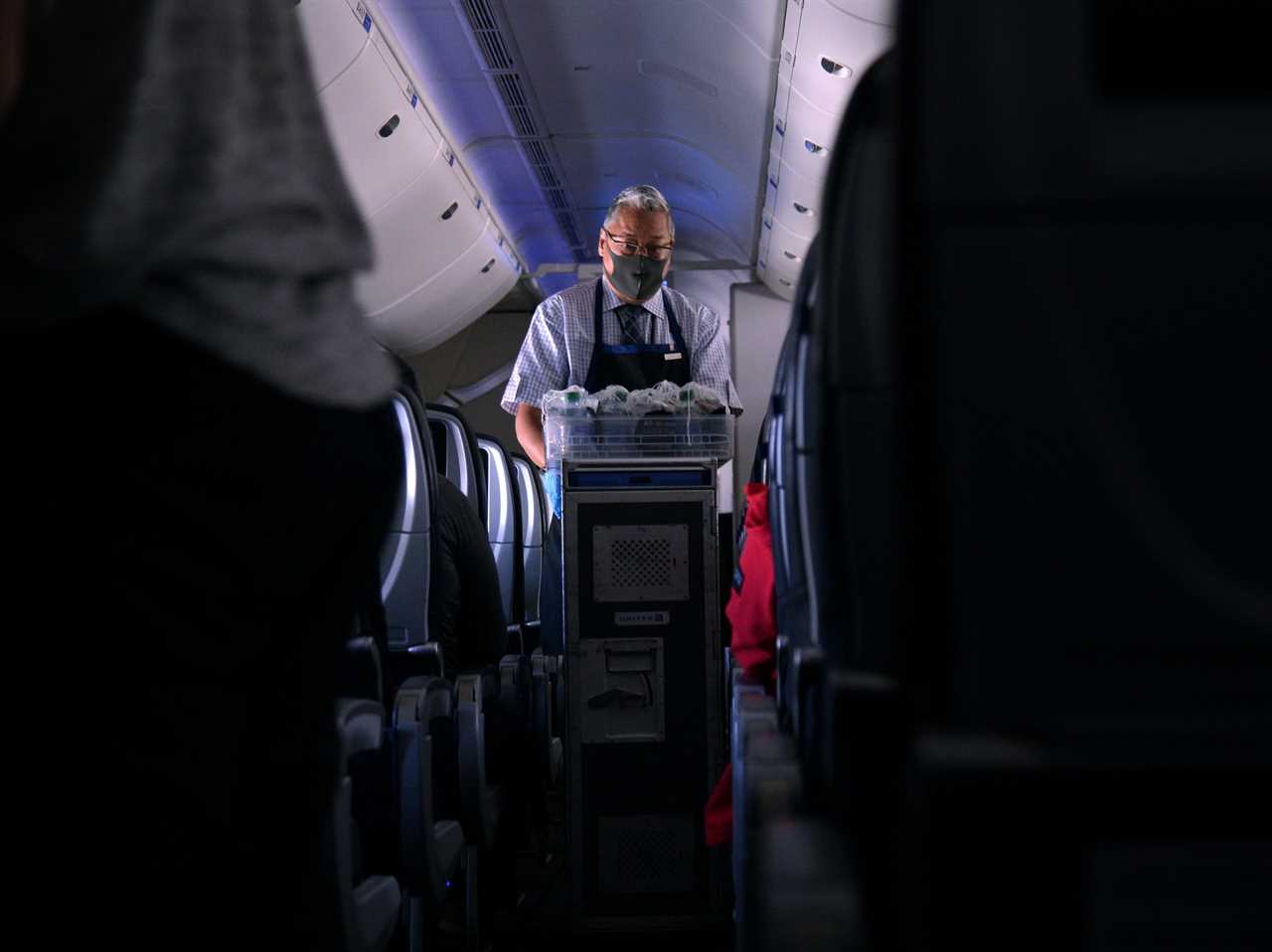 united airlines flight attendant gives drinks to passengers