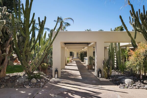 The main house is reached via a partially covered portico surrounded by native vegetation.