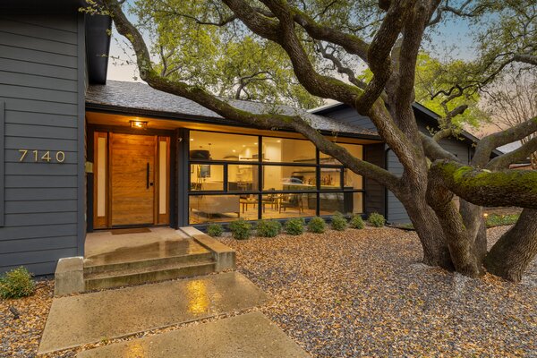 Wide concrete pads lead to the main entrance, where a large tree extends a warm welcome.