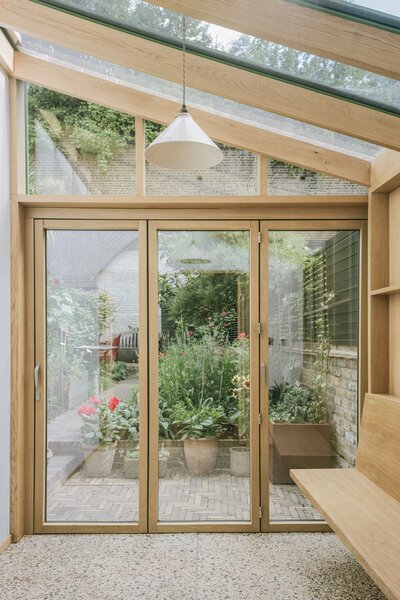 The glass house interior features a timber terrazzo floor made from recycled waste wood for a sense of playfulness, warmth, and harmony with the oak frame.