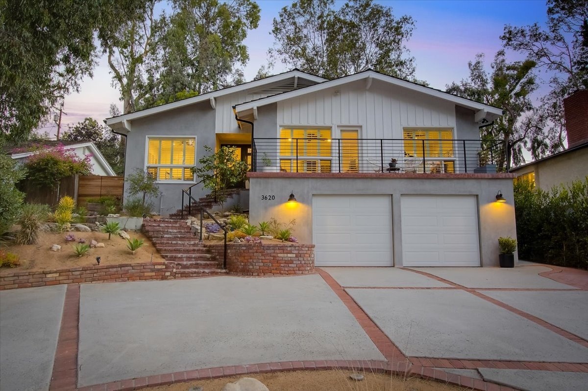 raised ranch home with plain exterior and brick walkway