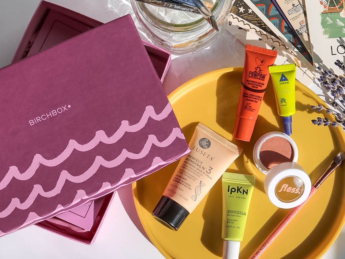 A Birchbox subscription box with assorted makeup and skincare items to its right one of the best subscription boxes