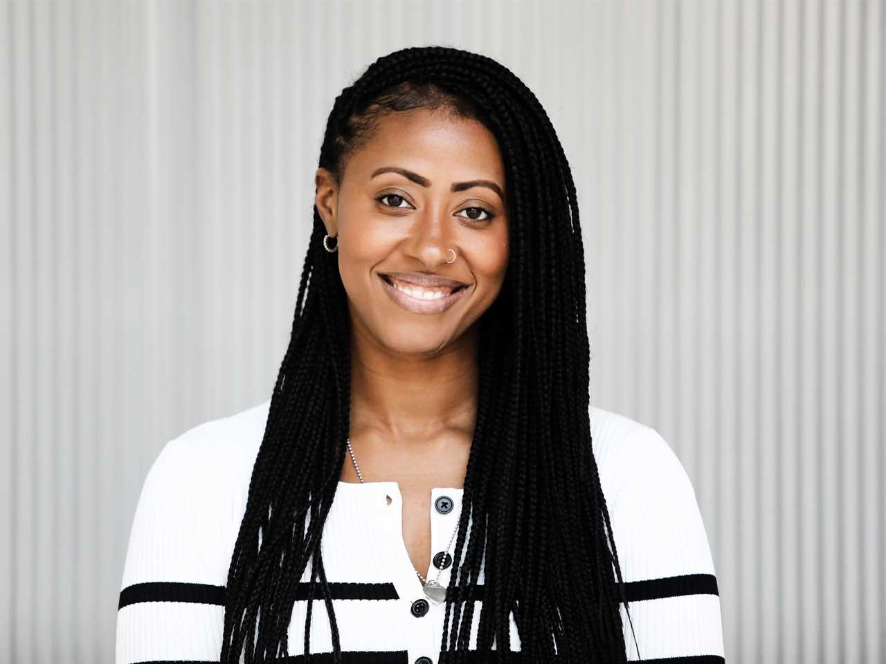 A headshot of Jamira Burley wearing a black and white striped top while standing in front of a white background.