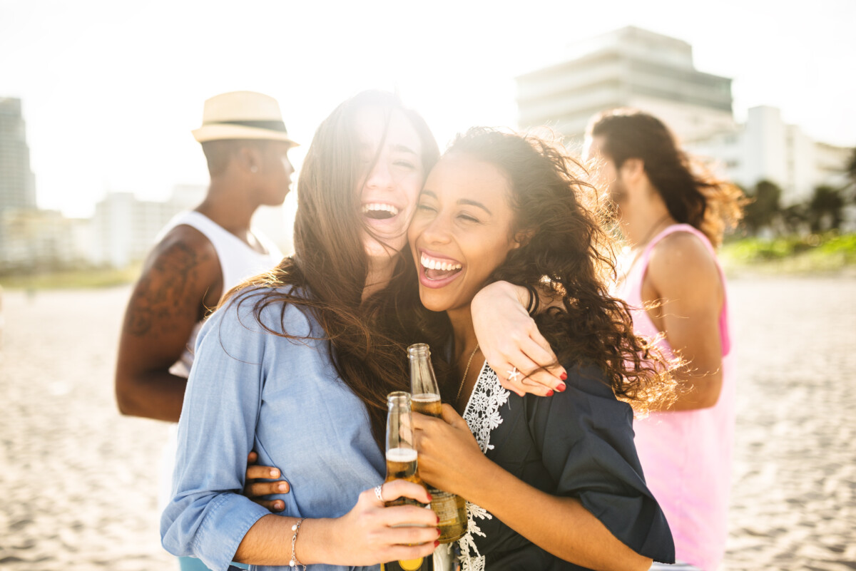 group of people cheering beers at dusk on the beach