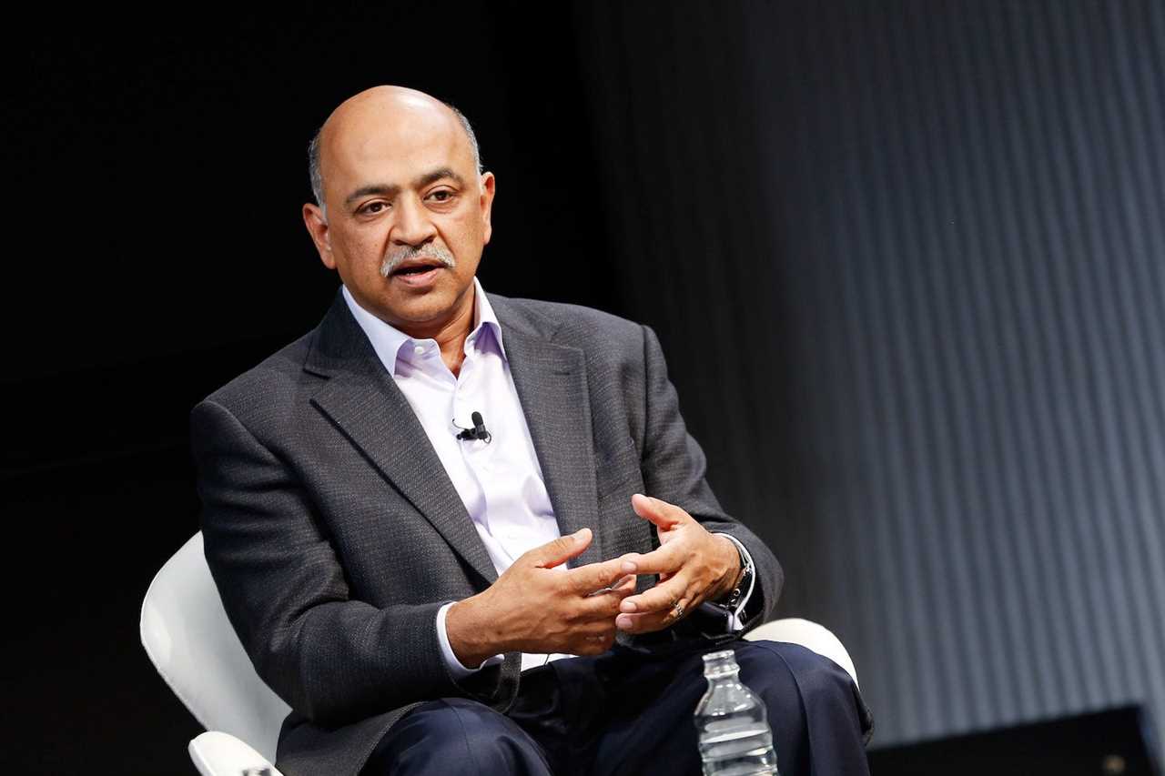 Arvind Krishna speaking to a crowd while sitting in a chair with his hands together.