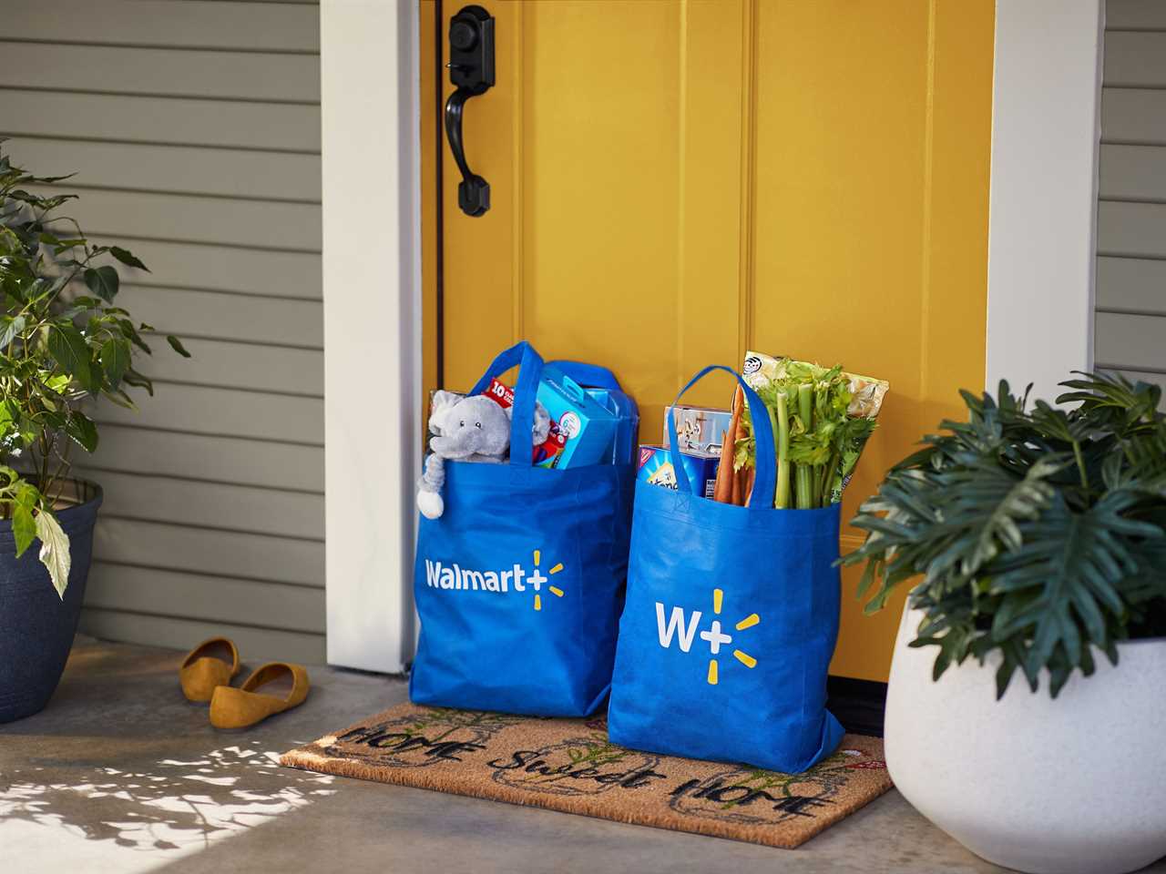 Two blue Walmart bags filled with groceries sitting on a doorstep.