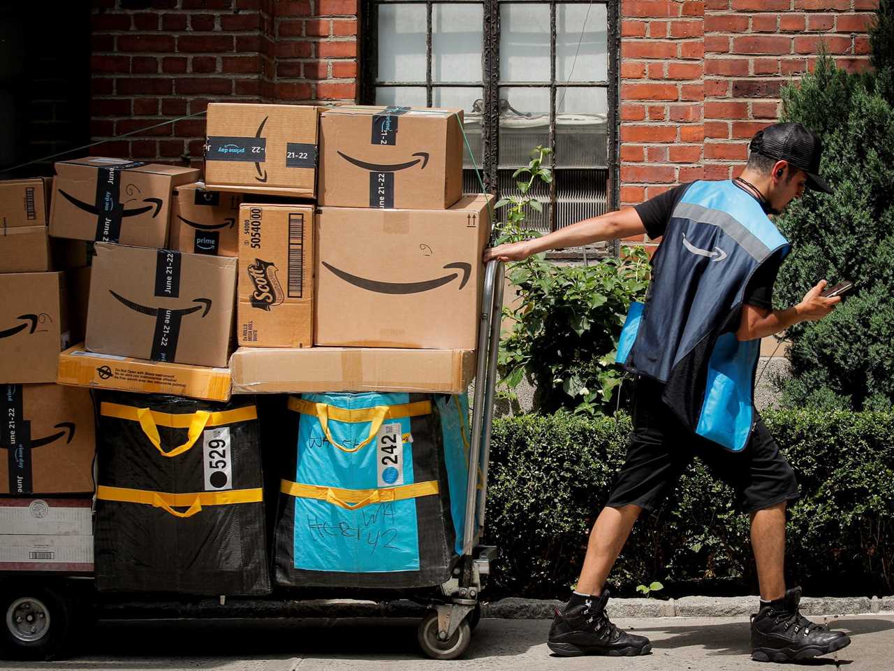 An Amazon worker pulls a cart full of Amazon packages.