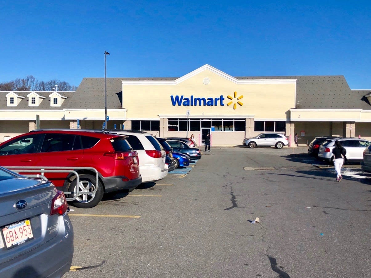 Cars sit in the parking lot of a Walmart store.