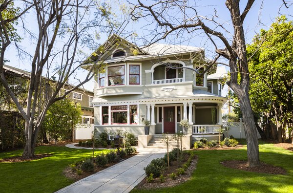 Framed by a white picket fence, the historic two-story home also has a wraparound porch.