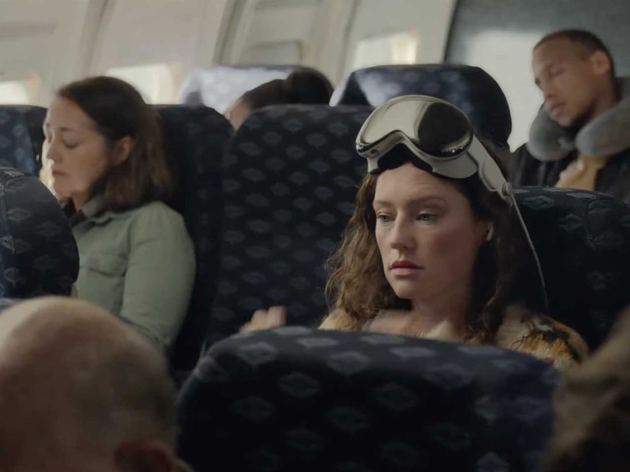 Woman seated in an airplane with Apple's Vision Pro on her head, like glasses.