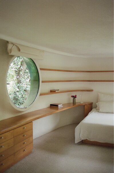 Inside, white plaster walls and wood shelving slope to match the curvature of the building.