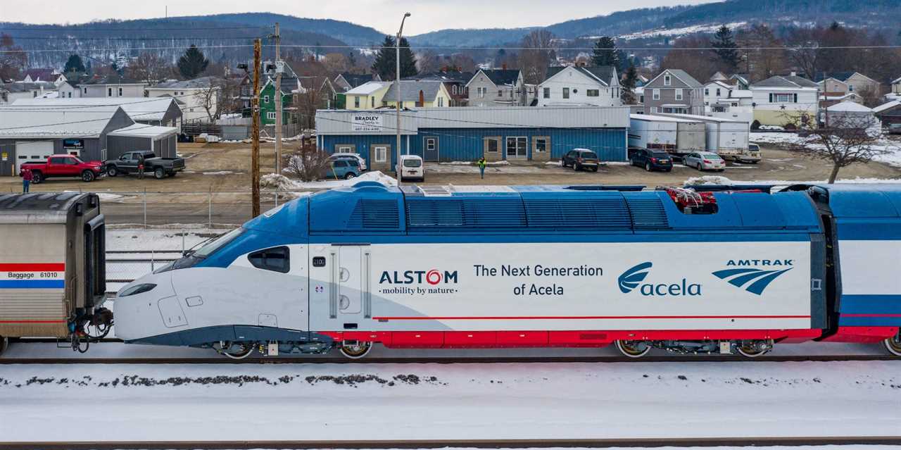 An Amtrak Acela train outside near homes.