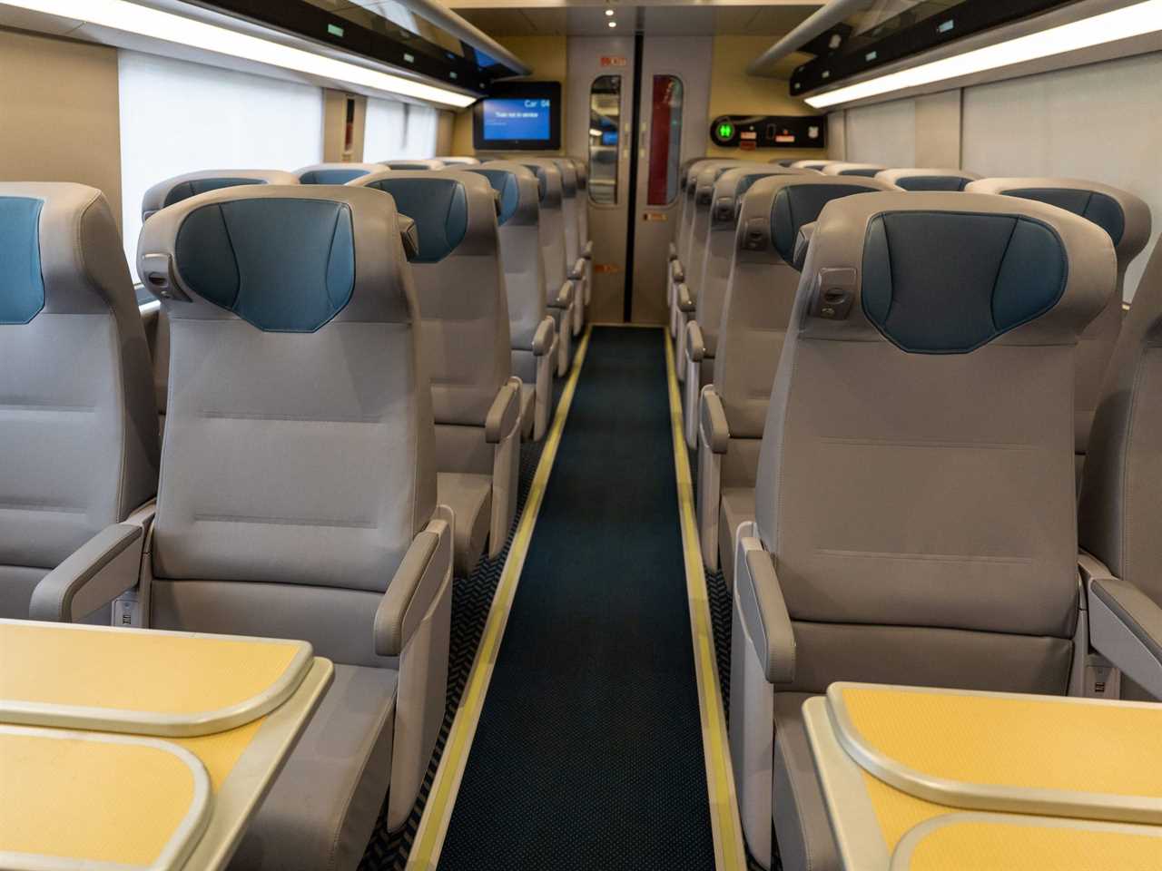 Rows of seats inside new Amtrak Acela interior, including seats with tables.