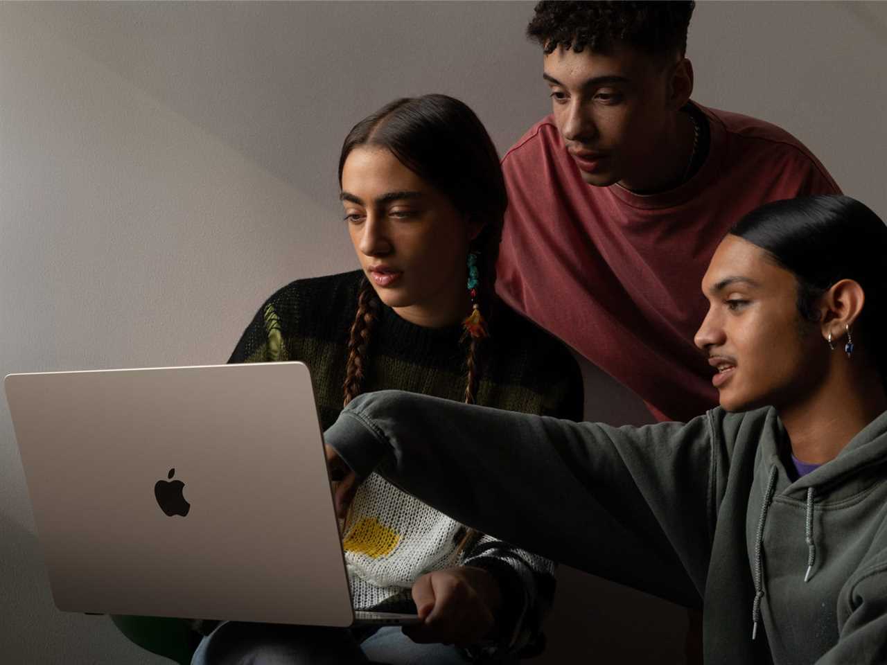 Three people looking at an Apple MacBook Air 15-inch laptop