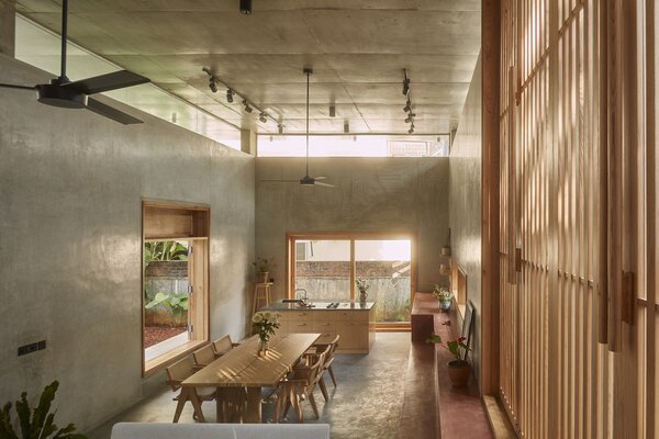 The double-height kitchen/dining/living area is finished primarily in concrete—but ash wood accents and large windows keep the atmosphere light.