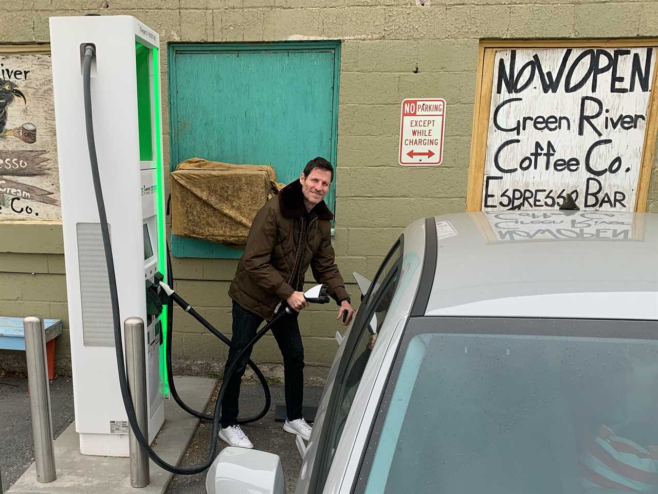 Man charging an electric car at a Electrify America charging station.