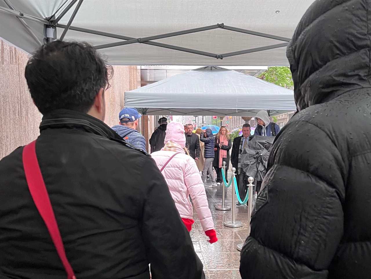 People stand under tent on rainy day outside Tiffany store in New York City