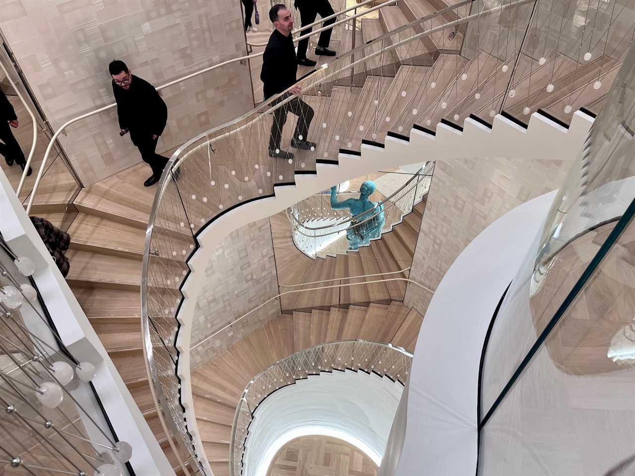 Two men pass on curved staircase inside Tiffany's store