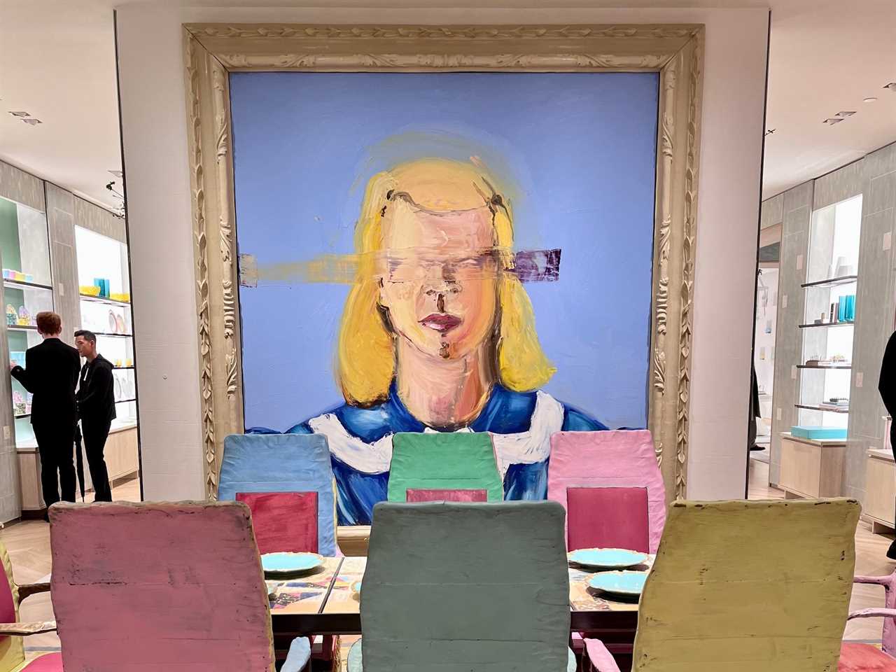 Large painting of a woman hangs on wall behind colorful dining chairs at Tiffany store