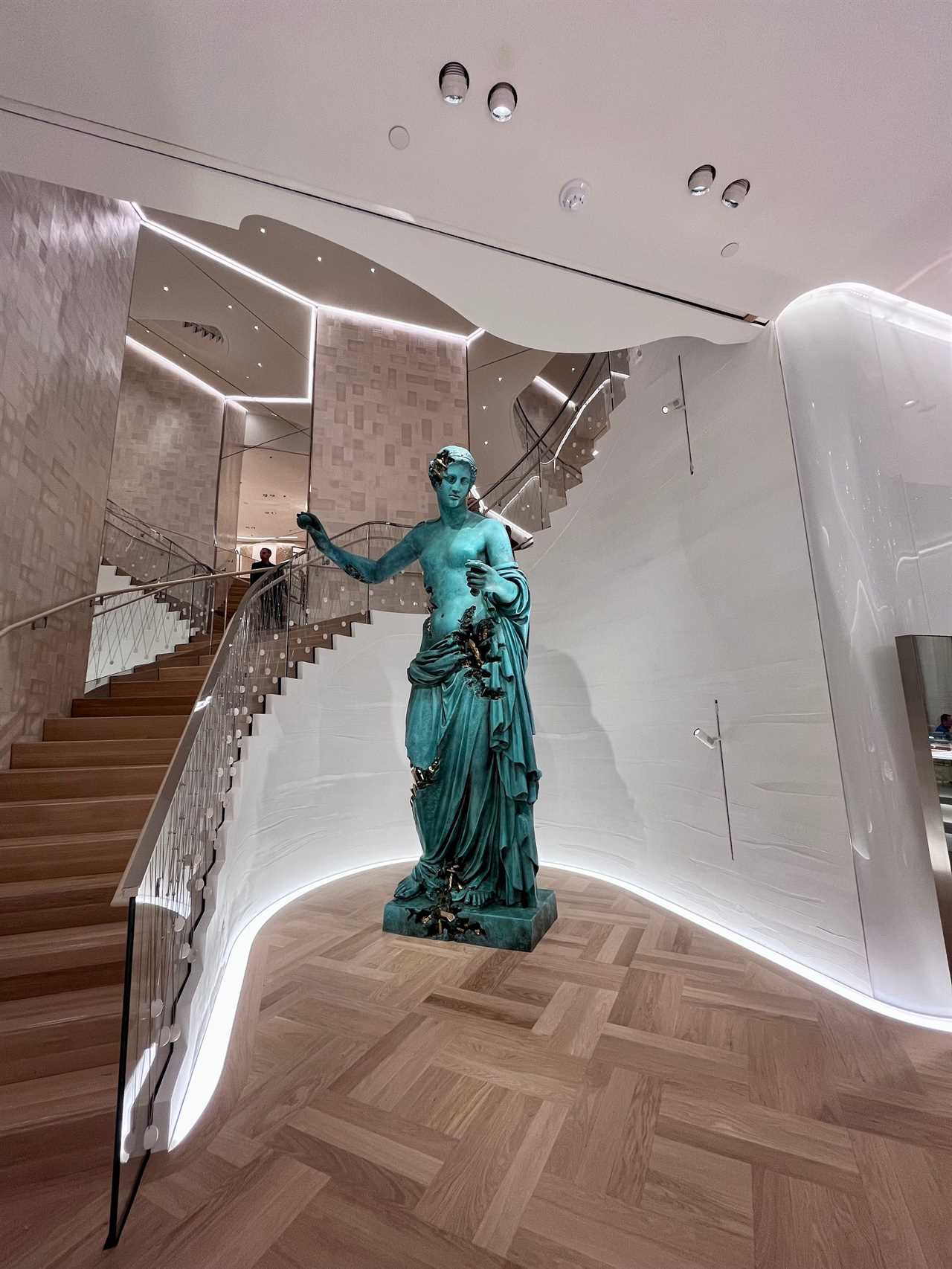 Venus statue at base of curved staircase inside Tiffany store