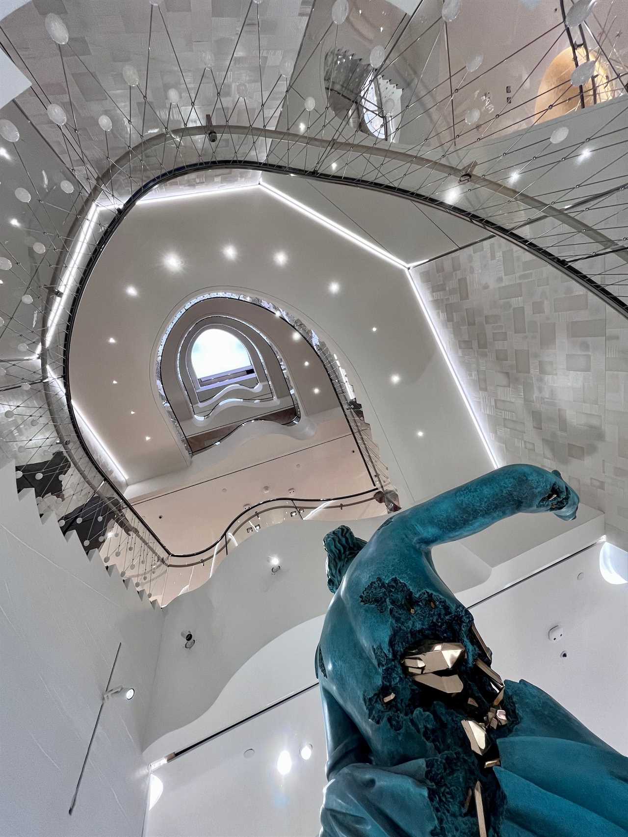 Statue in foreground of view up staircase to skylight at Tiffany store