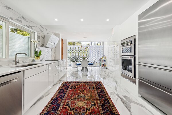 A bright and airy kitchen is located adjacent to the main great room and comes with custom white cabinetry, quartz countertops, and all new high-end appliances.