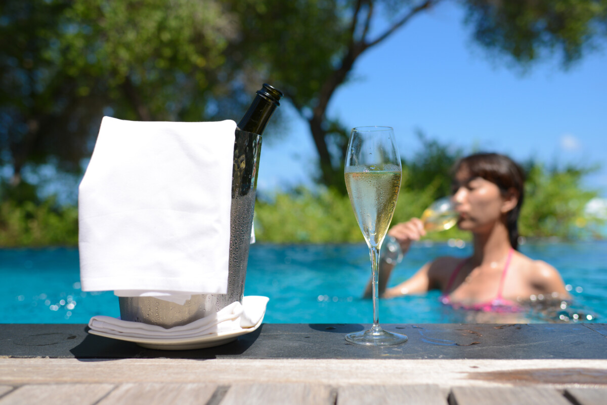 A girl in a pool drinking champagne