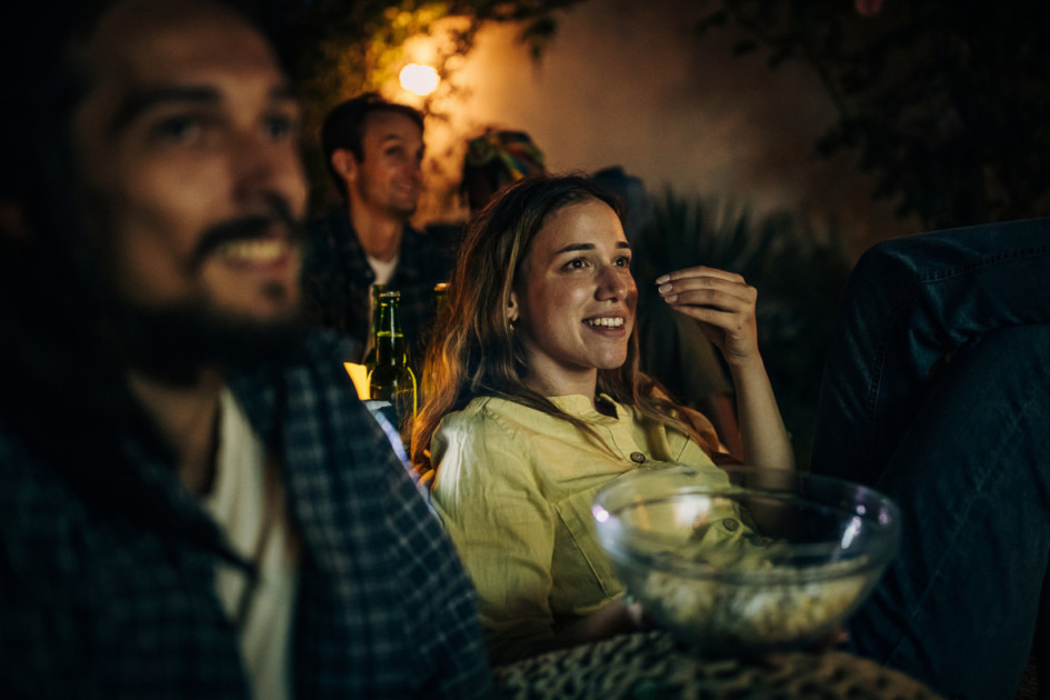 Friends watching movie on the video projector in the backyard garden