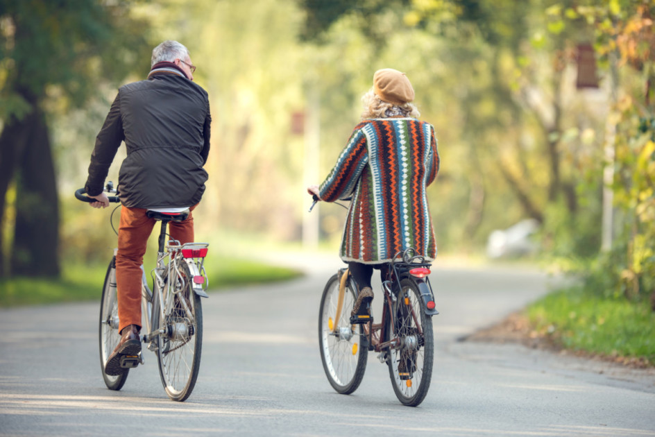 Back view of a couple riding bikes in the park.