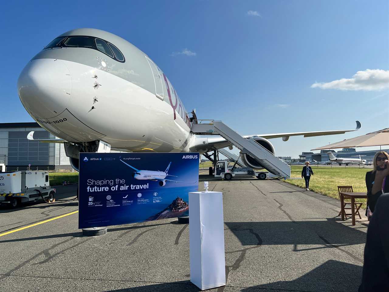 The front of a Qatar Airways Airbus A350 with a promotional sign, and stairway on the side, at the Paris Air Show.