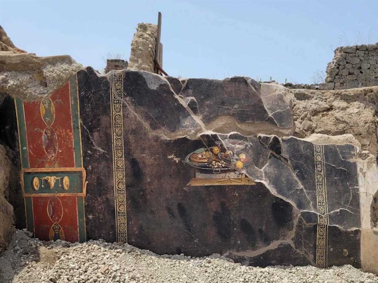 A photo shows the ruins featuring the fresco in situ, set against a blue sky.