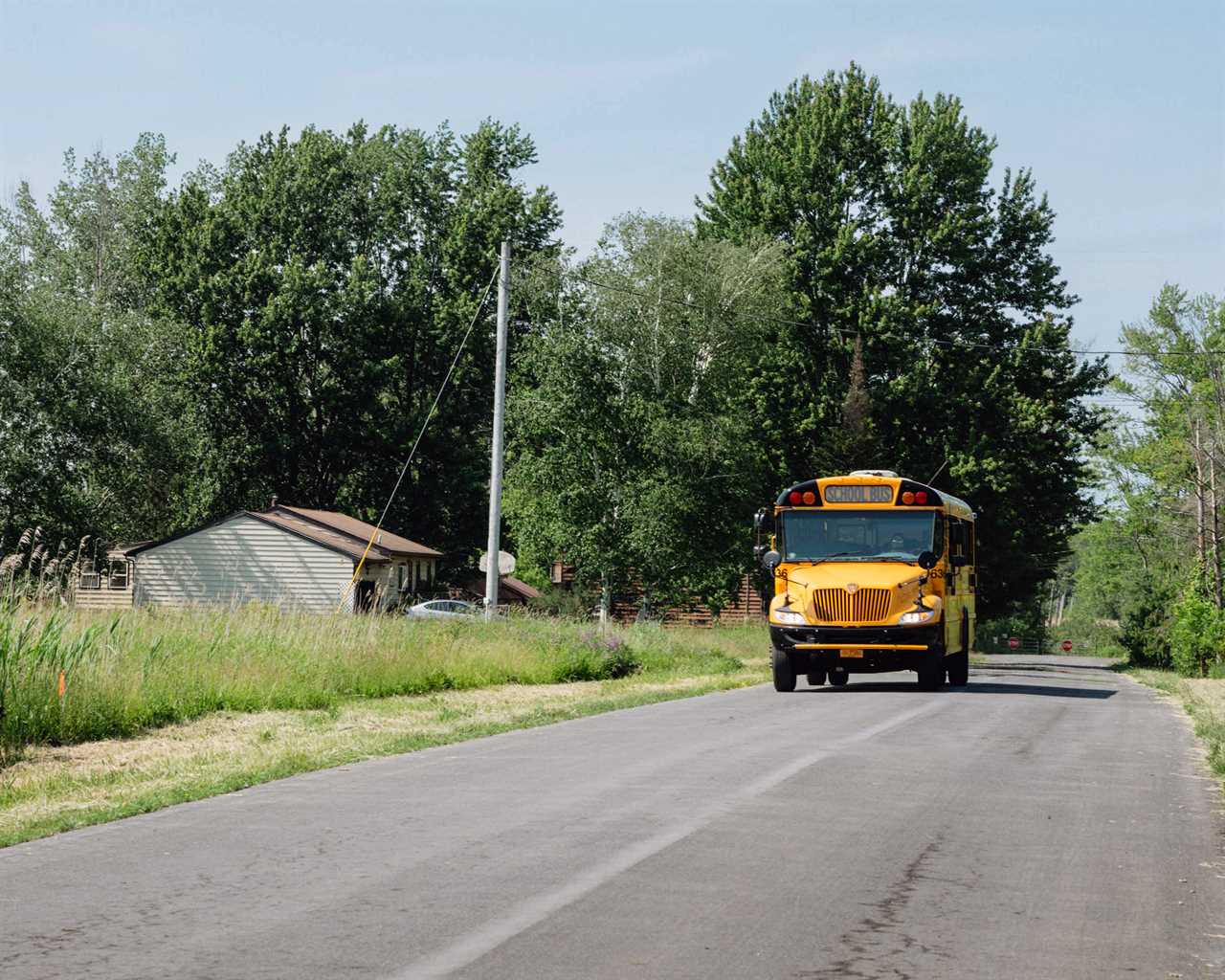 A school bus drives down a rural street in New York.