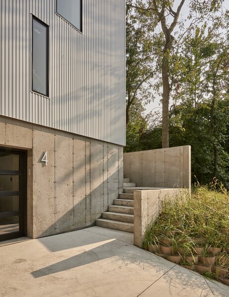 The home's exterior materials of concrete and white metal siding were chosen to help the home defer to its lush natural surroundings. "With the white metal, the trees reflect and create shadow play,