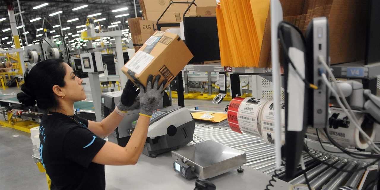 An Amazon worker with a package at a fulfillment center