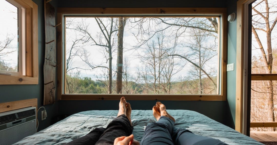 A couple holding hands inside one of the treehouses known as Cliff Dweller.